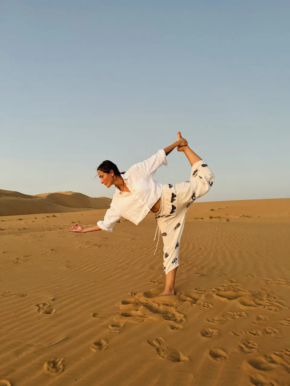 Anna practising a standing bow pose in the desert
